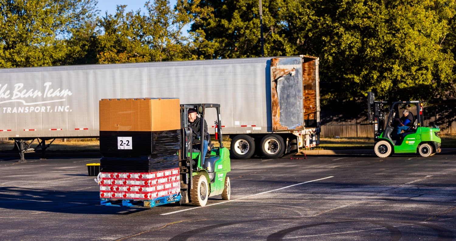 Forklift loading a wrapped pallet onto a trailer for wholesale delivery